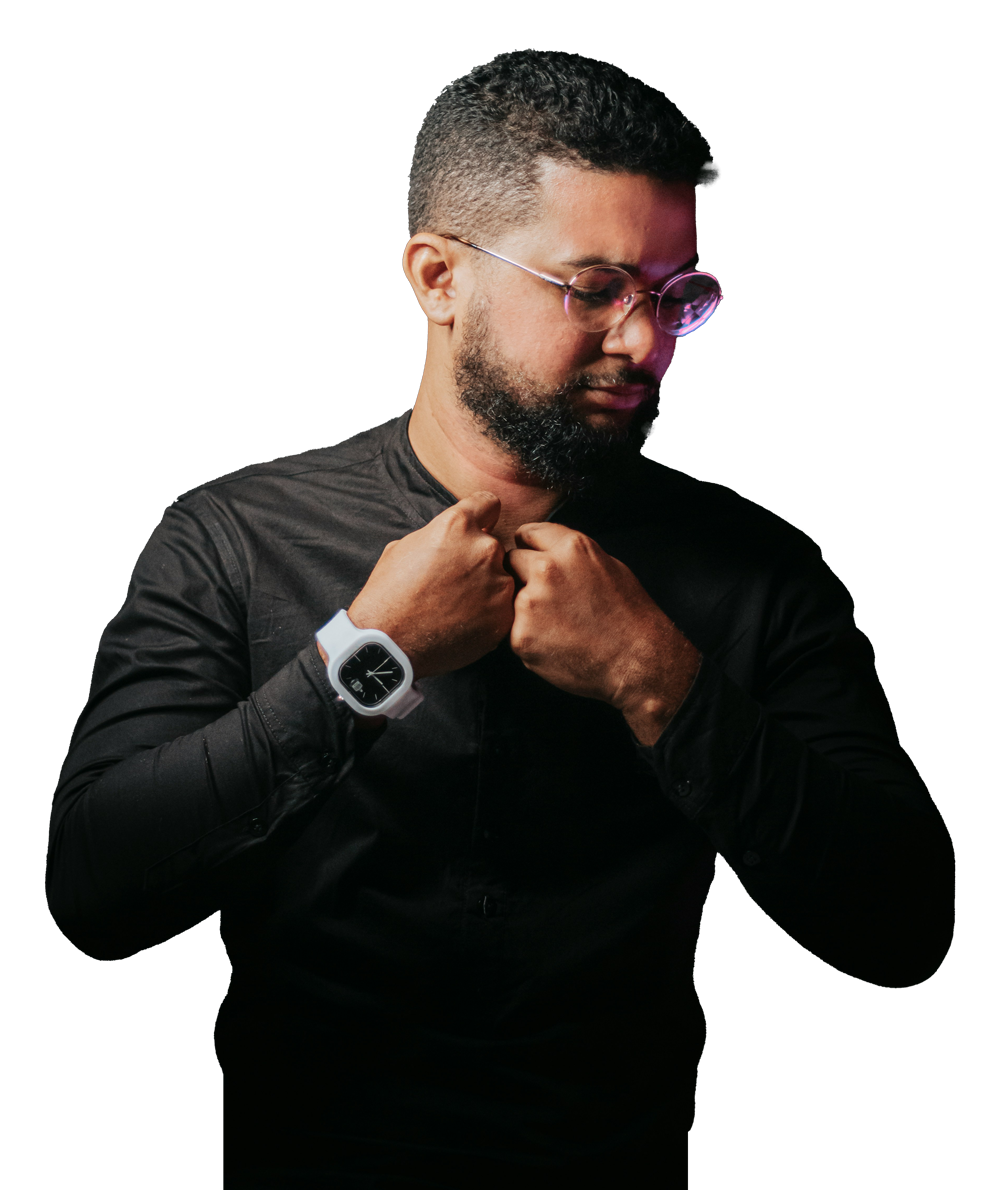 Hombre con barba y gafas, vistiéndo una camiseta negra y ajustándose el cuello.