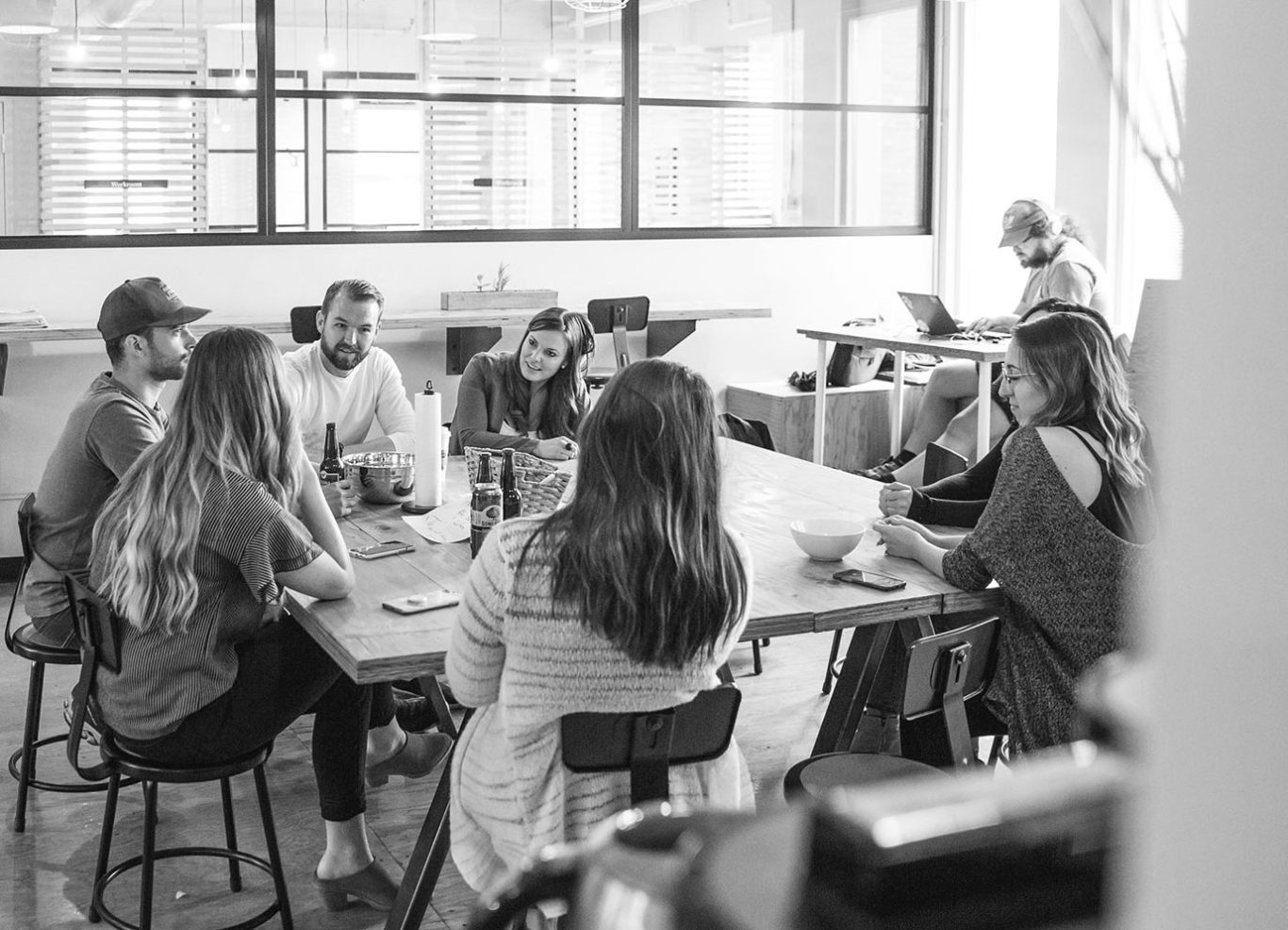 Grupo de personas sentadas alrededor de una mesa, conversando en un ambiente colaborativo.